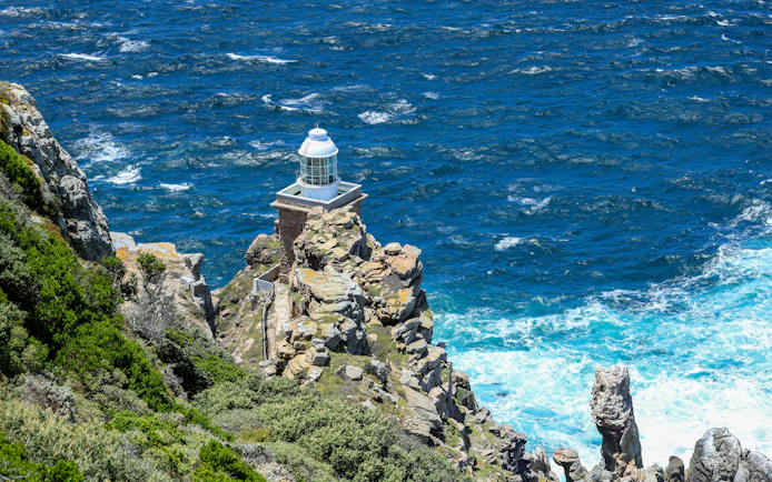 Cape Point lighthouse on rocky cliff overlooking the ocean in South Africa.