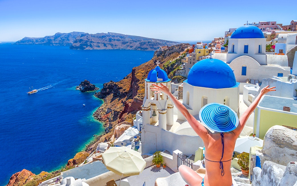 Oia town on Santorini island with blue-domed churches and Aegean Sea view.
