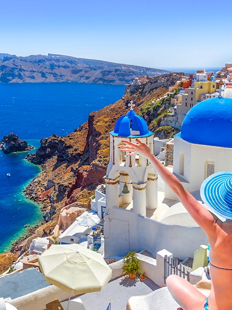 Oia town on Santorini island with blue-domed churches and Aegean Sea view.