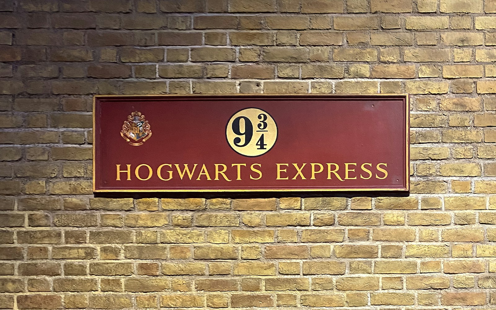 Platform 9¾ sign at Harry Potter studio tour, featuring Hogwarts Express emblem.
