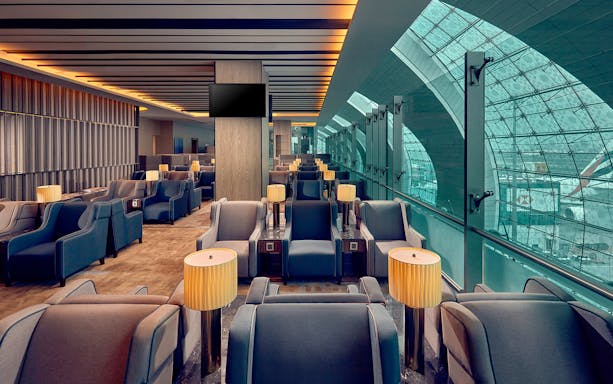 Plaza Premium Lounge seating area at Dubai International Airport with armchairs and lamps.