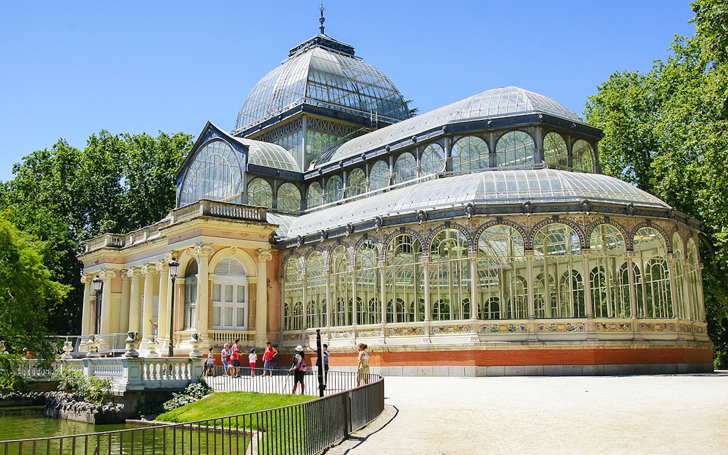 Crystal Palace in Retiro Park, Madrid, with visitors outside.