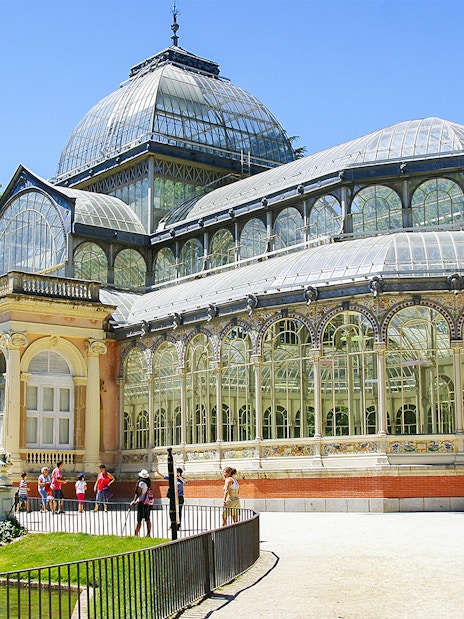 Crystal Palace in Retiro Park, Madrid, with visitors outside.