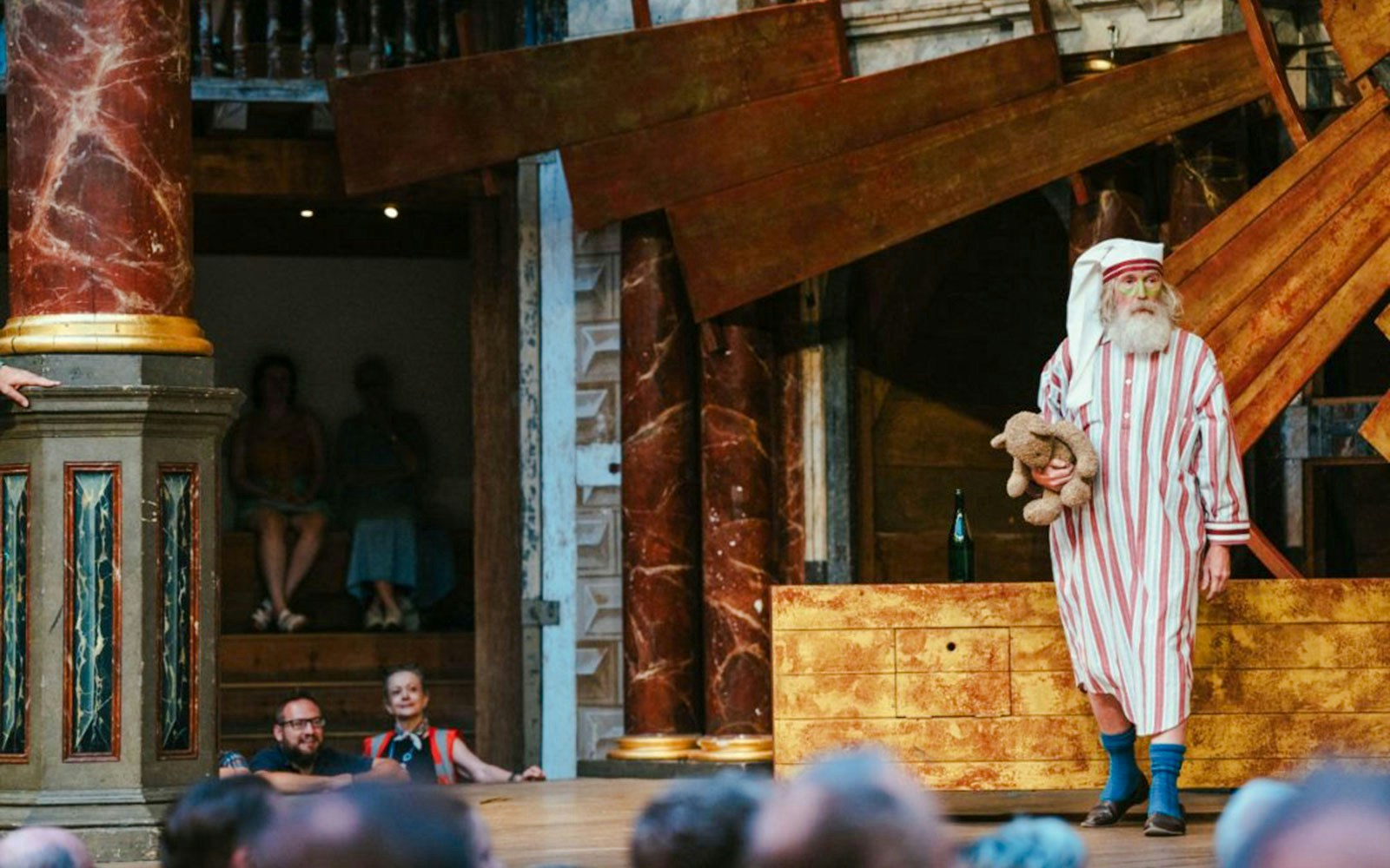 Actor in striped nightgown holding teddy bear during Twelfth Night performance at Globe Theatre.