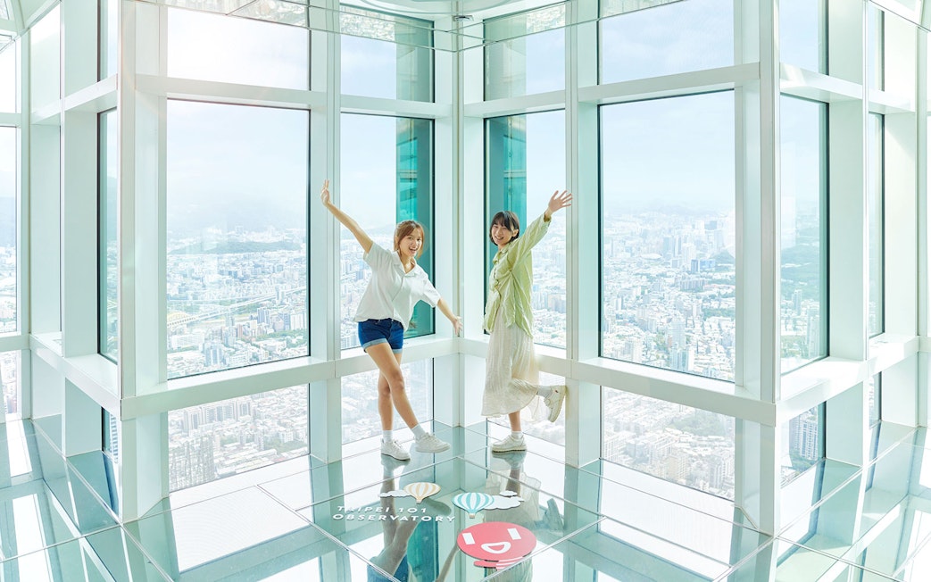Visitors enjoying the view from Taipei 101 Observatory with cityscape in the background.