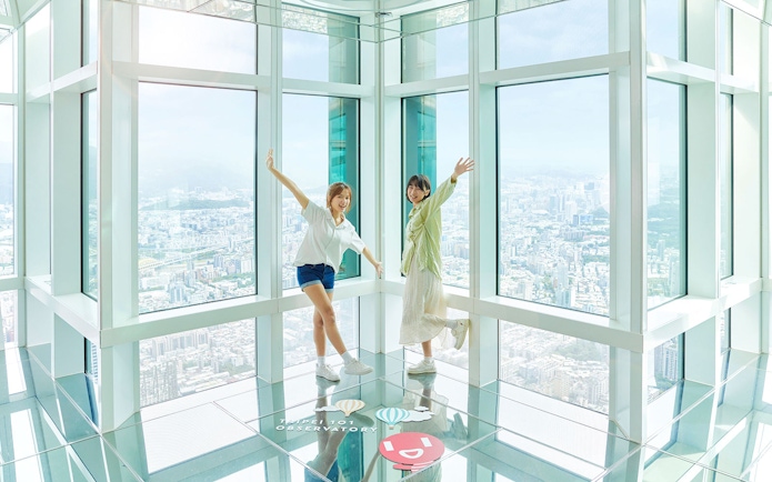 Visitors enjoying the view from Taipei 101 Observatory with cityscape in the background.