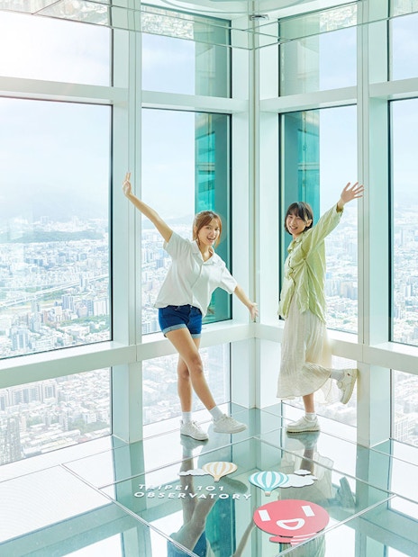 Visitors enjoying the view from Taipei 101 Observatory with cityscape in the background.
