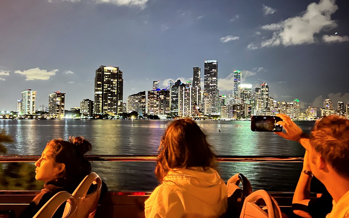 Passengers on Big Bus Miami Night Tour viewing illuminated Miami skyline.