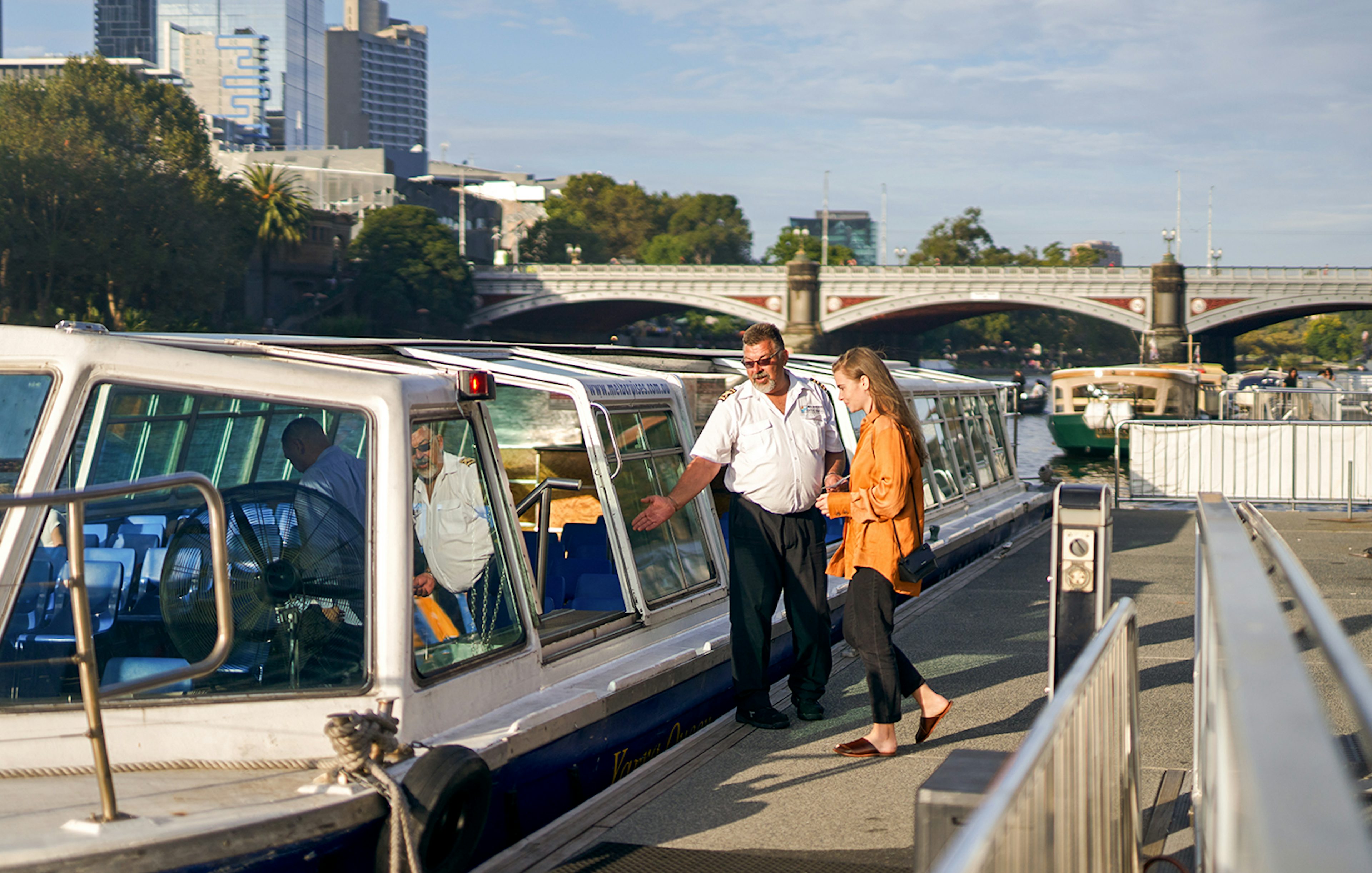 Cruise captain checking guest tickets on Yarra River sightseeing cruise in Melbourne.