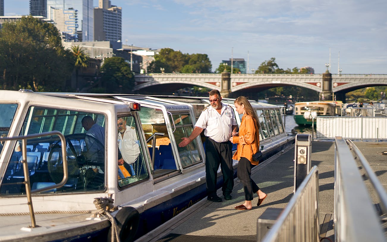 Cruise captain checking guest tickets on Yarra River sightseeing cruise in Melbourne.