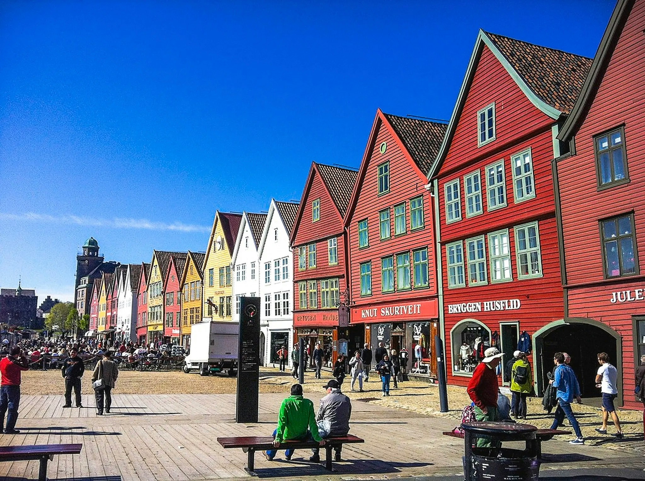 Colorful wooden buildings at Bryggen Hanseatic Wharf in Bergen, Norway, with people walking nearby.