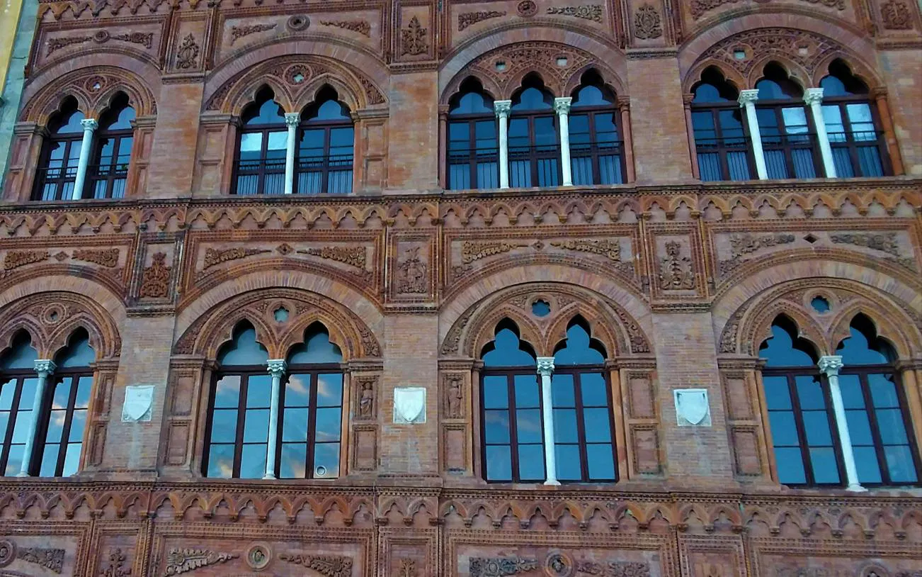 Ornate facade of historic building in Pisa, featuring arched windows and intricate brickwork.