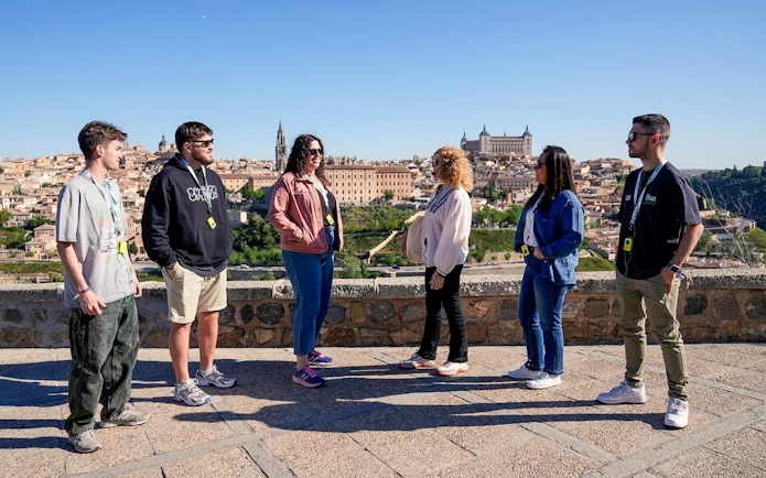 Group of tourists on a guided tour overlooking Toledo, Spain, with historic buildings in the background.