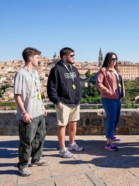 Group of tourists on a guided tour overlooking Toledo, Spain, with historic buildings in the background.
