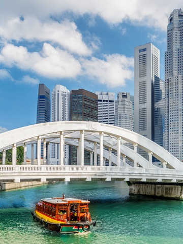 Boat cruising under Elgin Bridge with Singapore skyline in the background.