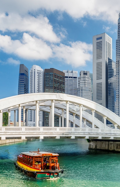Boat cruising under Elgin Bridge with Singapore skyline in the background.