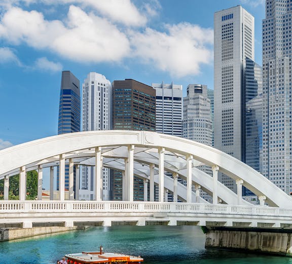 Boat cruising under Elgin Bridge with Singapore skyline in the background.