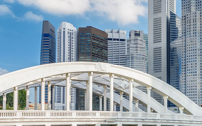 Boat cruising under Elgin Bridge with Singapore skyline in the background.