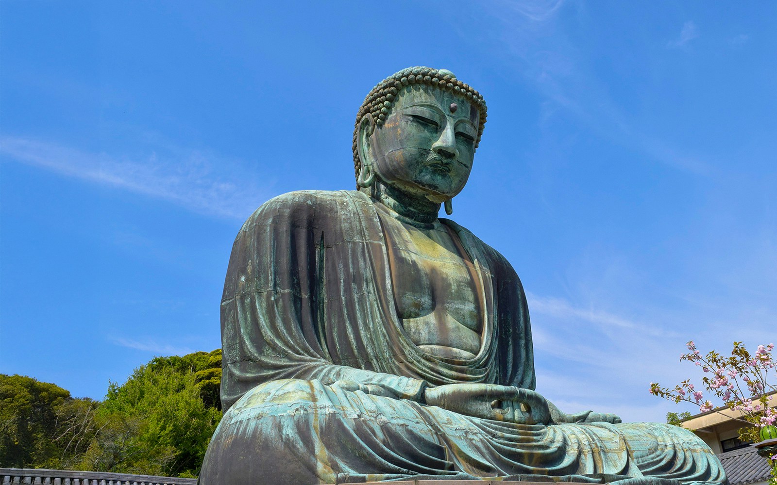 Great Buddha of Kamakura with tourists exploring the surrounding temple grounds.