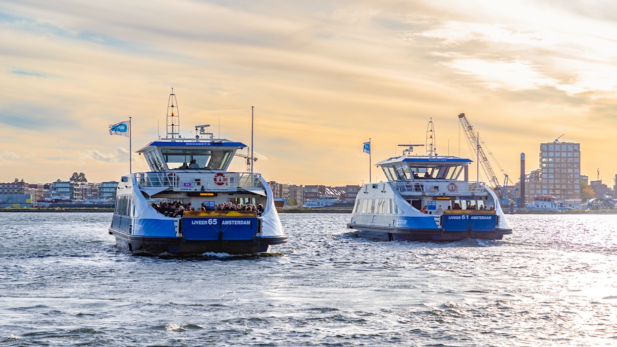 Amsterdam GVB ferry crossing a canal with cityscape in the background.