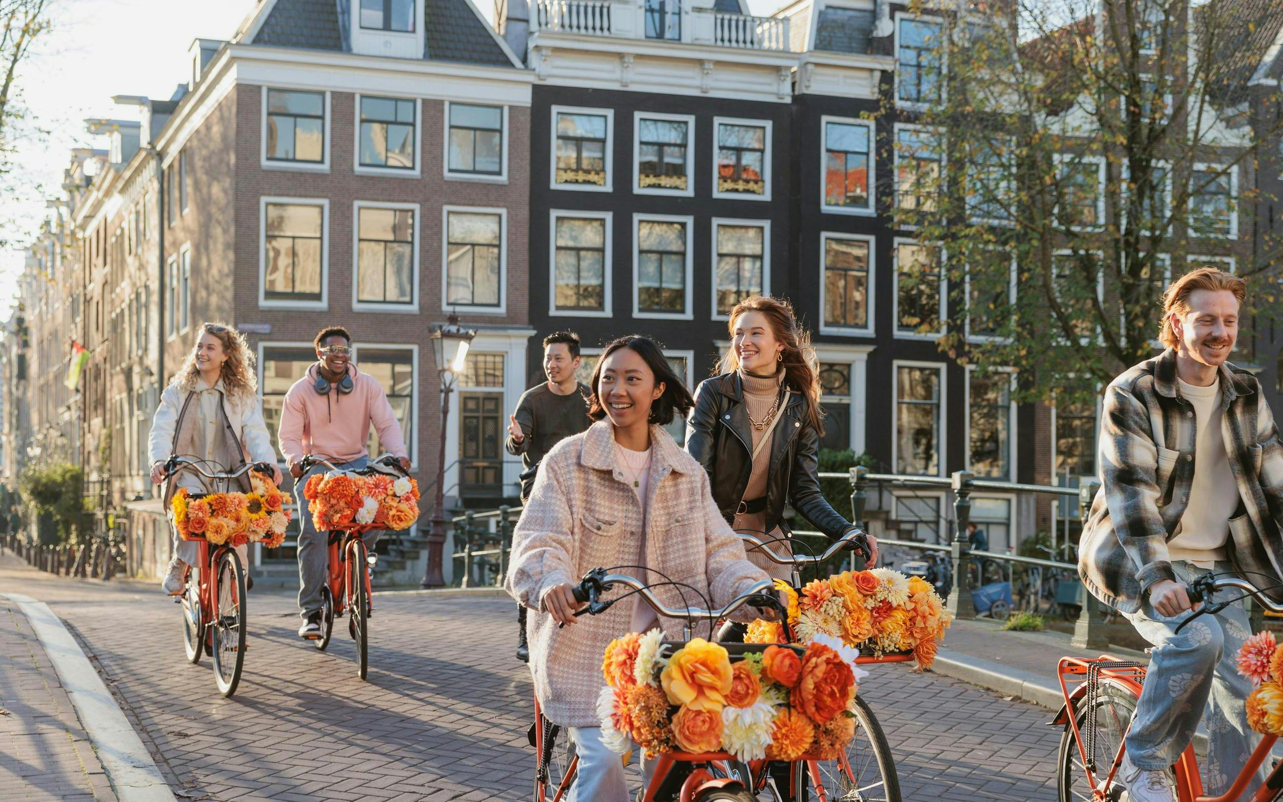 Group biking along a canal in Amsterdam on a city highlights tour.