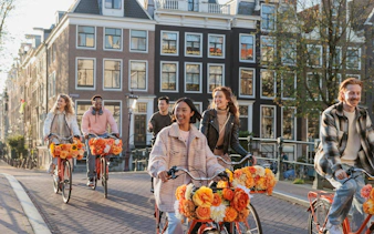 Group biking along a canal in Amsterdam on a city highlights tour.
