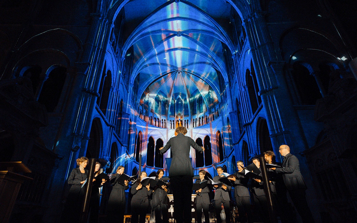 Choir performing under colorful lights at LUMINISCENCE Manchester 360° Immersive Show.
