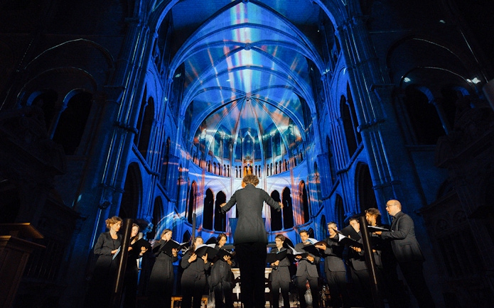 Choir performing under colorful lights at LUMINISCENCE Manchester 360° Immersive Show.