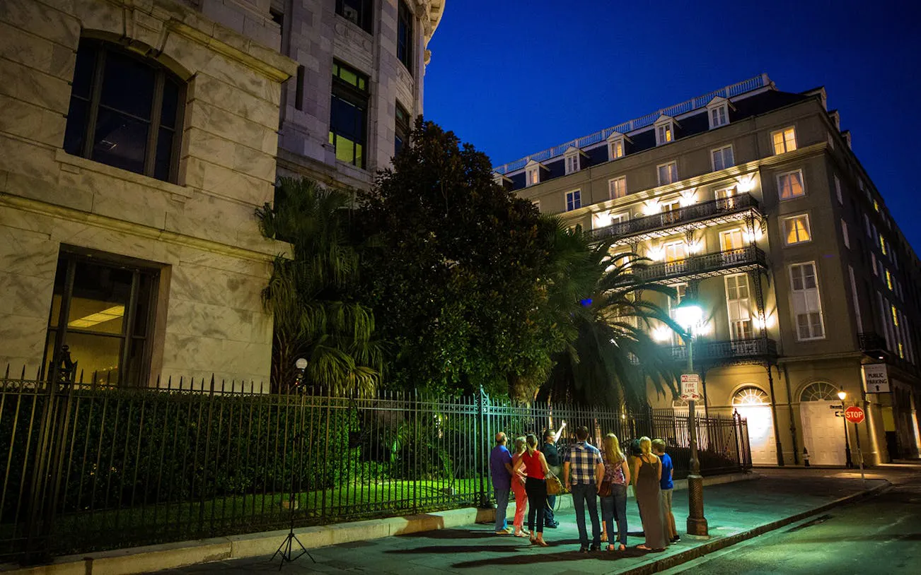 Group on New Orleans ghost tour at night near historic buildings.