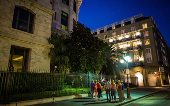 Group on New Orleans ghost tour at night near historic buildings.