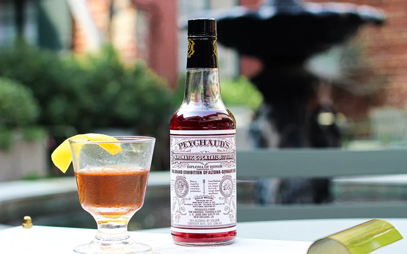 Peychaud's bitters bottle and cocktail with lemon garnish on New Orleans Craft Cocktail Walking Tour.