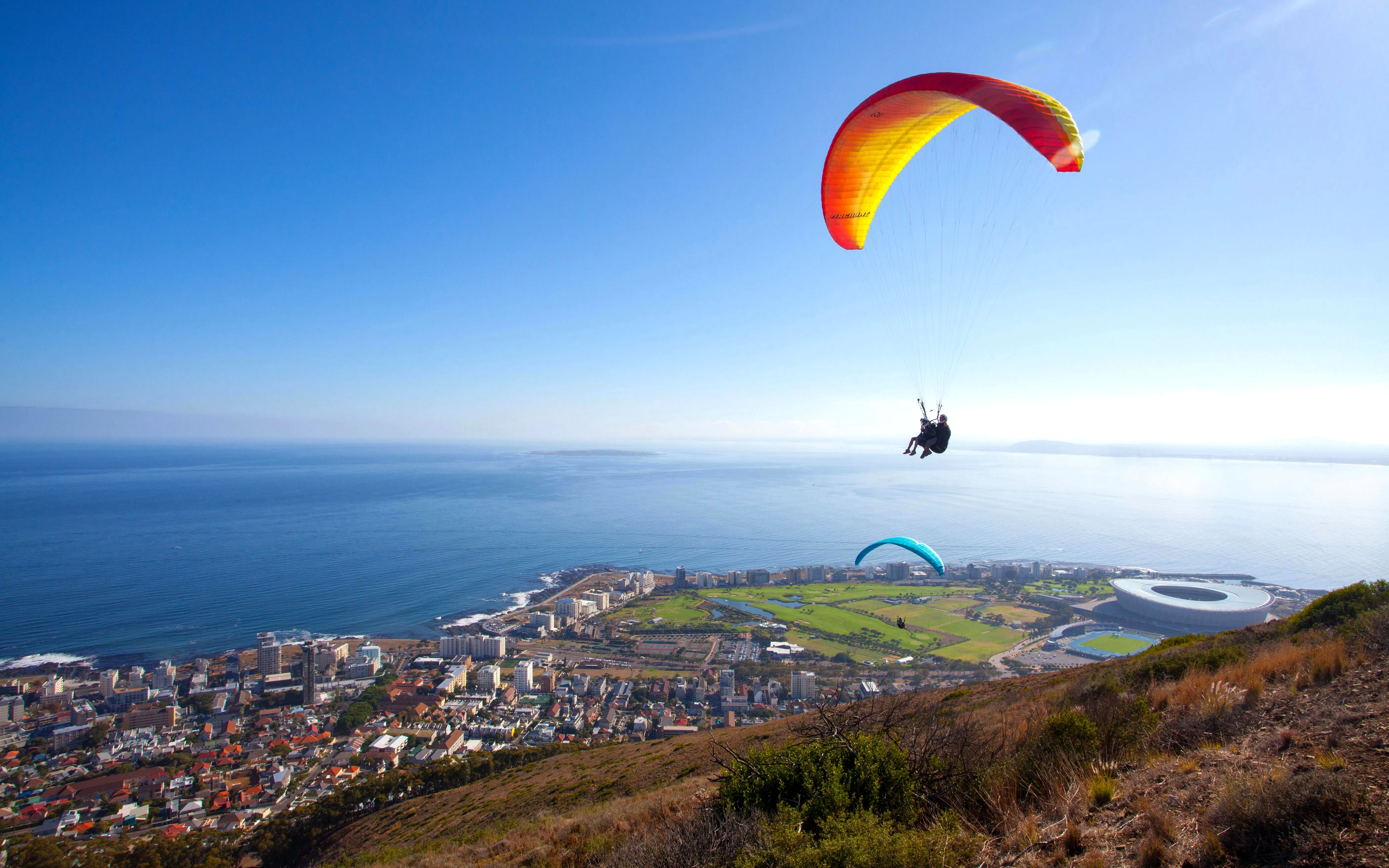 Paragliders soaring over Cape Town with ocean and cityscape views.