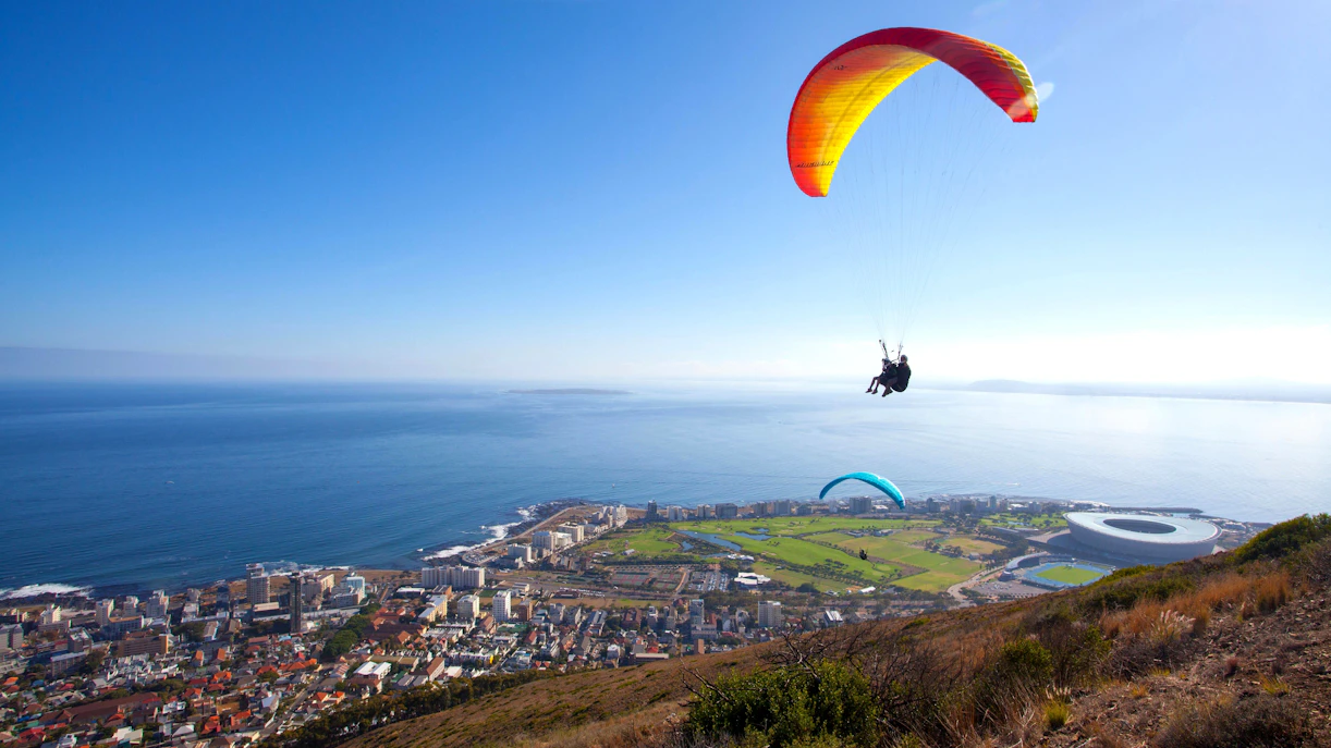 Paragliders soaring over Cape Town with ocean and cityscape views.