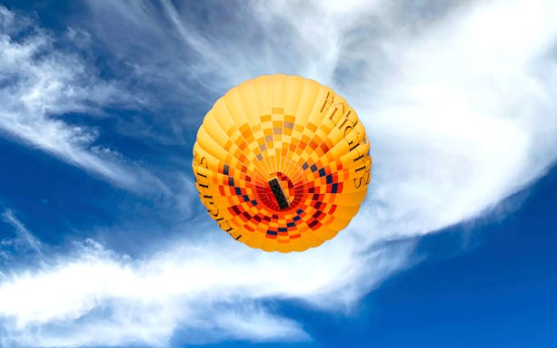 Hot air balloon soaring against a blue sky during a flight tour.