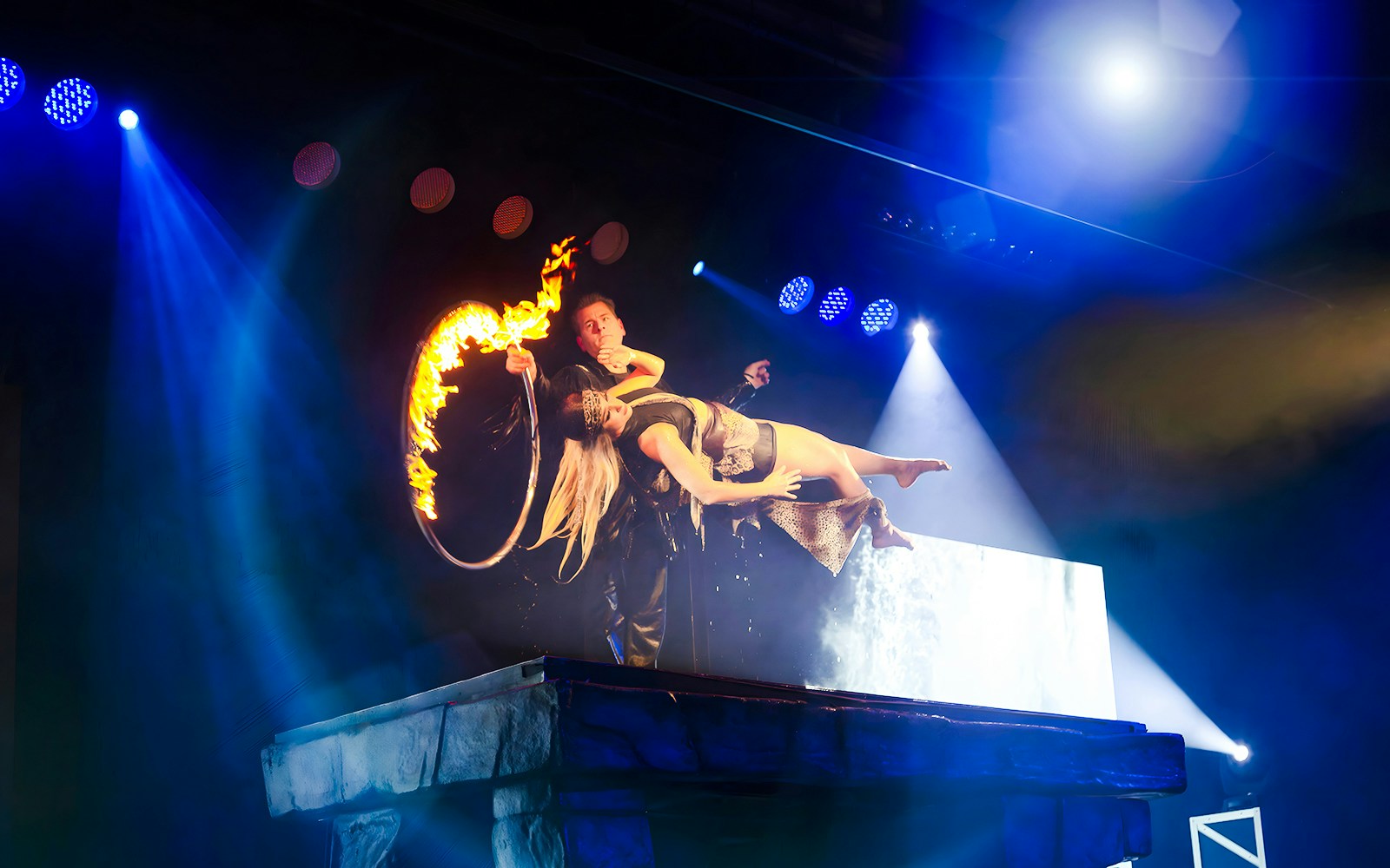 Magician levitates assistant through flaming hoop at Evolution Magic Show.