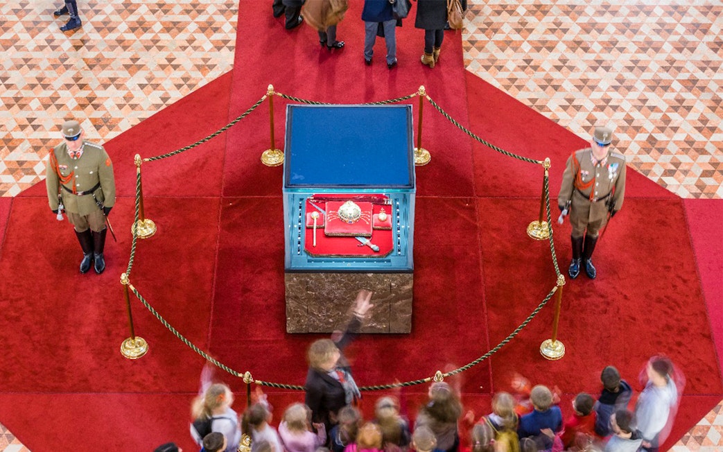 Hungarian Parliament crown jewels display with guards and visitors in Budapest.