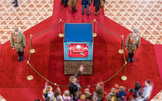 Hungarian Parliament crown jewels display with guards and visitors in Budapest.