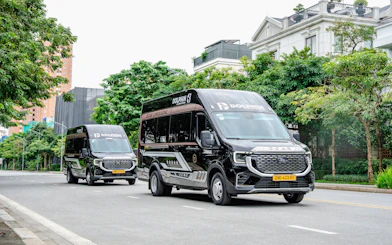 Dolphin Transfer vans driving on a tree-lined street.