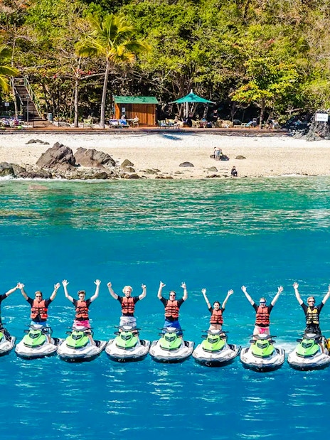 Tourists on jetskis in formation near Whitsundays beach, aerial view.