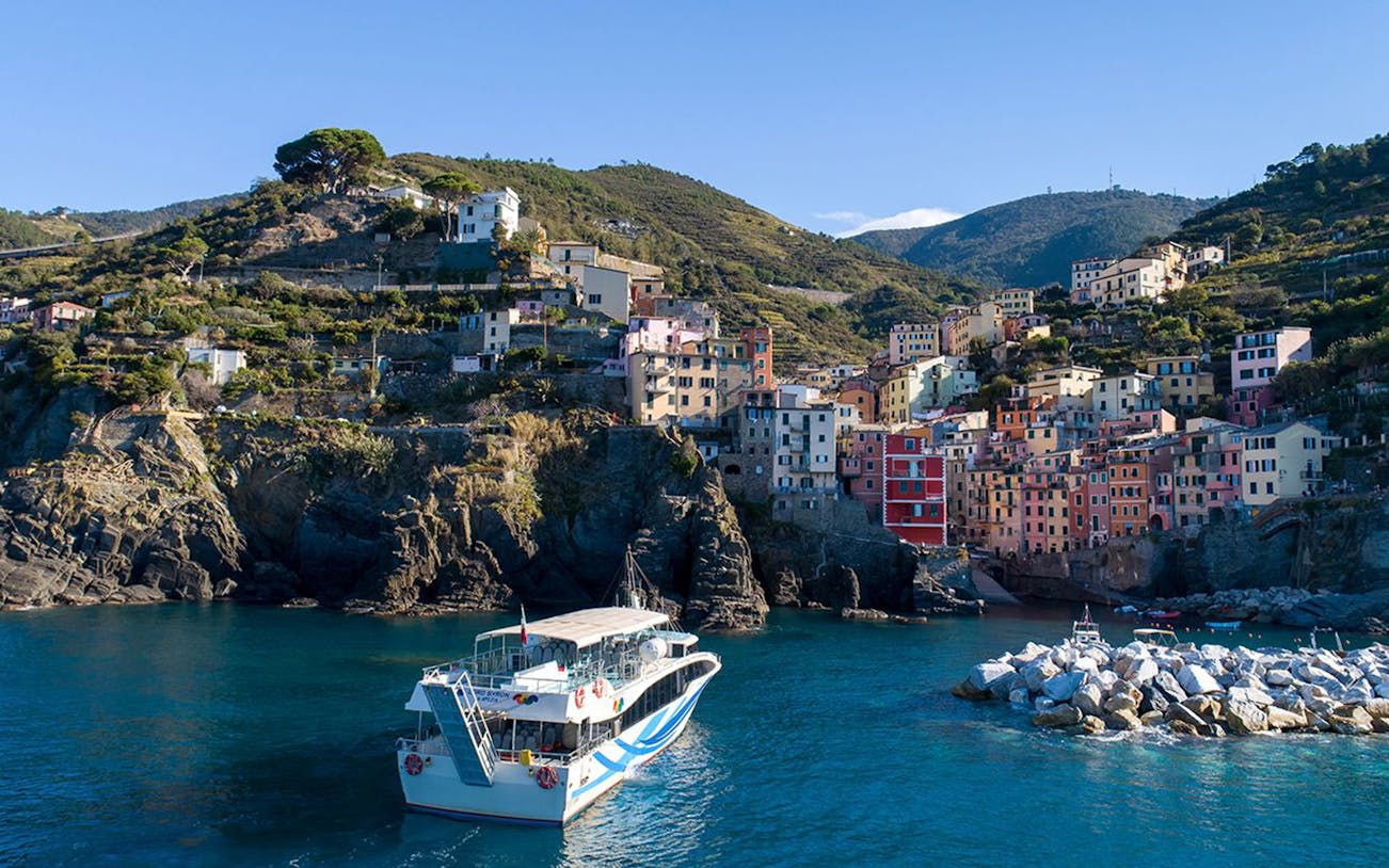 Boat approaching colorful cliffside village of Riomaggiore, Cinque Terre, Italy.