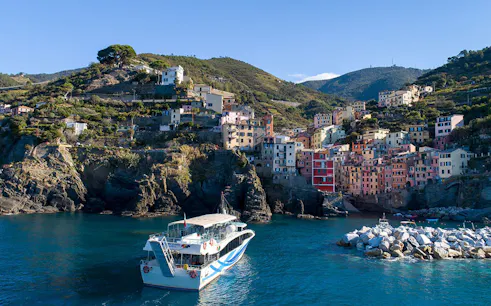 Boat approaching colorful cliffside village of Riomaggiore, Cinque Terre, Italy.
