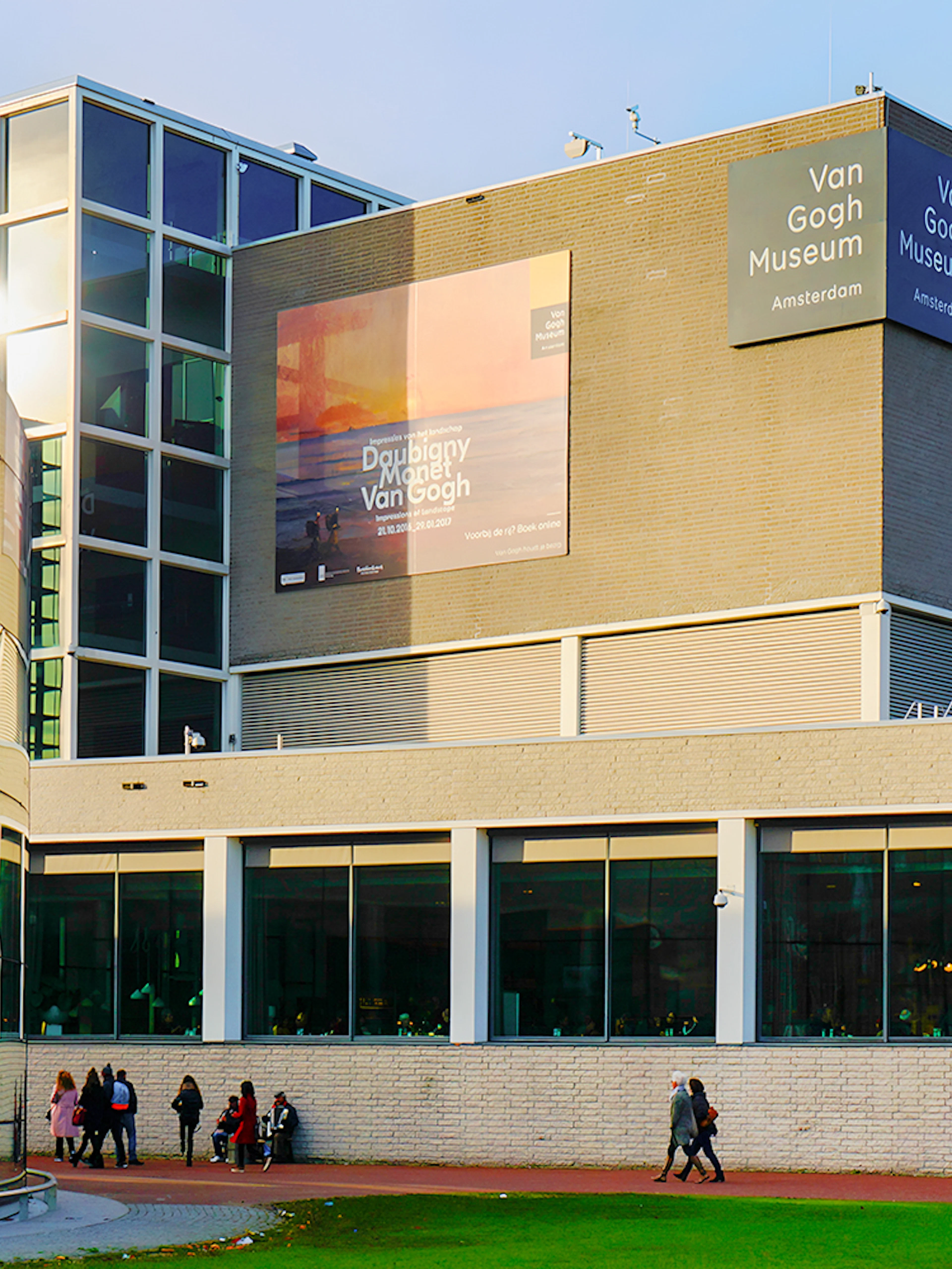 Van Gogh Museum exterior in Amsterdam with visitors walking nearby.