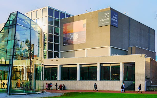 Van Gogh Museum exterior in Amsterdam with visitors walking nearby.