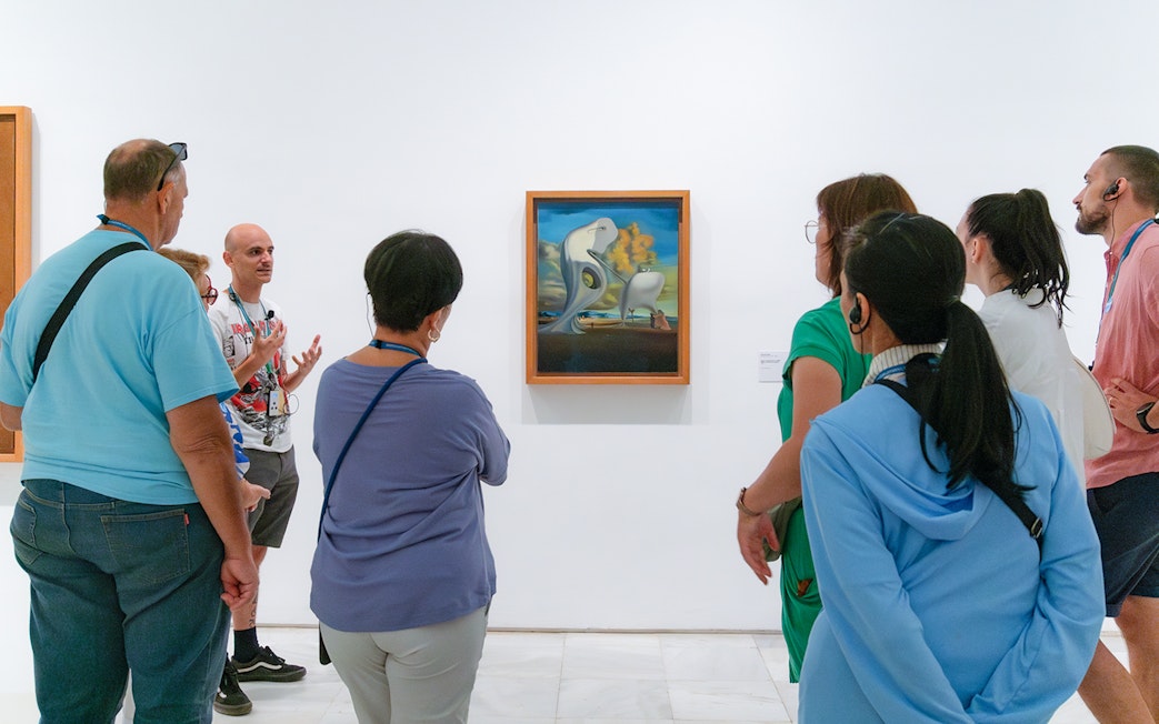 Visitors on a guided tour at Prado Museum viewing surrealist painting.