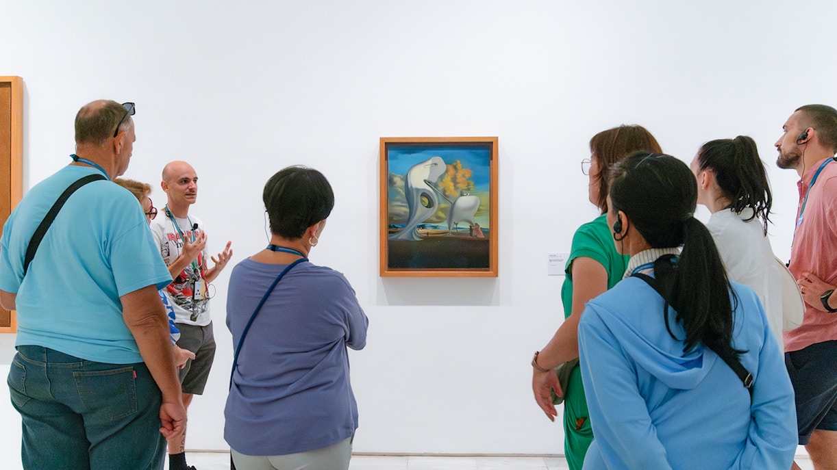 Visitors on a guided tour at Prado Museum viewing surrealist painting.