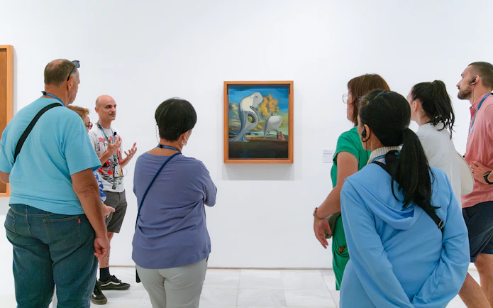 Visitors on a guided tour at Prado Museum viewing surrealist painting.