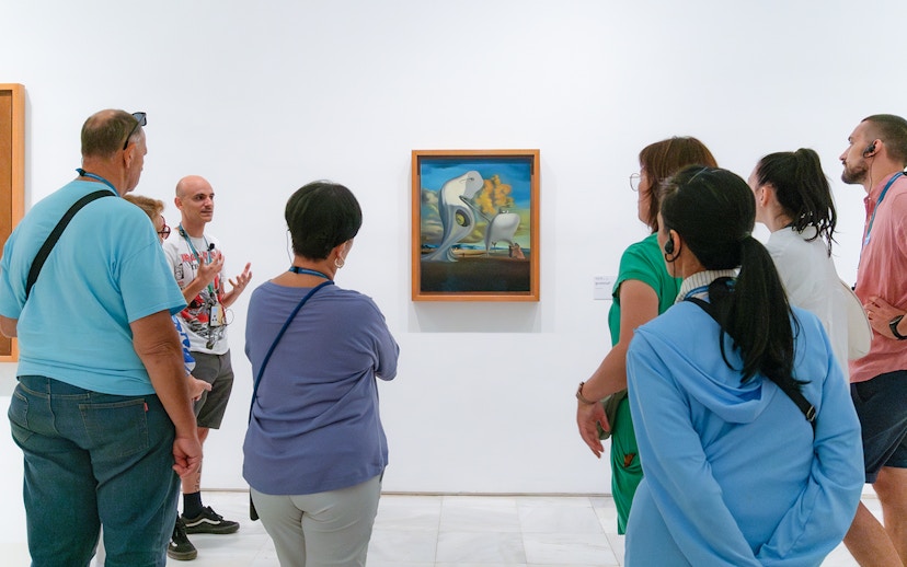 Visitors on a guided tour at Prado Museum viewing surrealist painting.