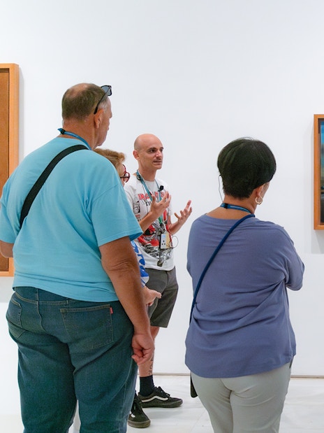 Visitors on a guided tour at Prado Museum viewing surrealist painting.