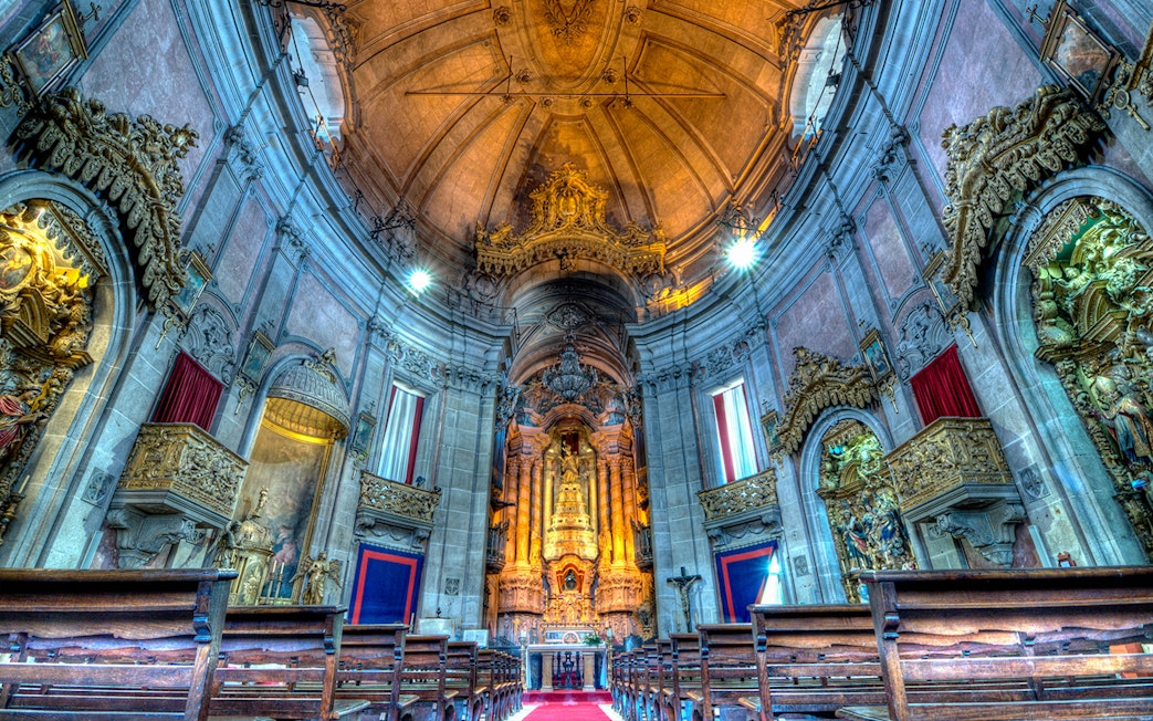 Clérigos Church interior with ornate altar and wooden pews, Porto, Portugal.