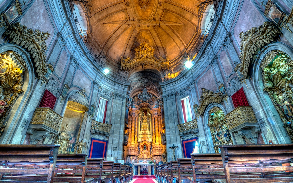 Clérigos Church interior with ornate altar and wooden pews, Porto, Portugal.
